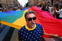 Gilbert Baker Leading the Stockholm Pride Parade Holding the Front of a Very Long Original Colors Pride Flag in 2003