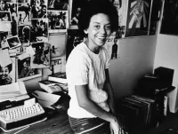 Nikki Giovanni Sitting on her Home Office Desk With Her Typewriter and Various Posters on the Wall in 1973