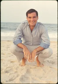 Larry Kramer Crouching on the Beach in Dress Casual Clothes in 1978